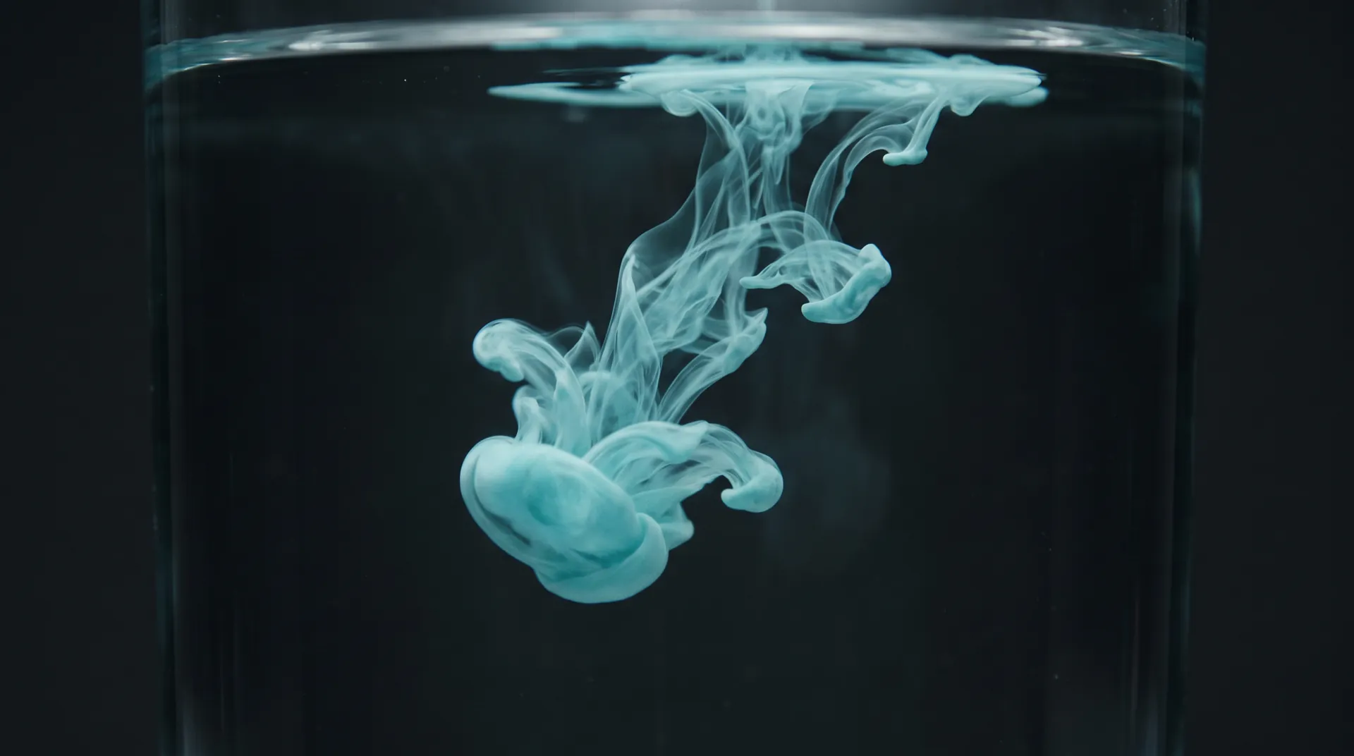 A plume of pale blue pigment unfolding in clear water